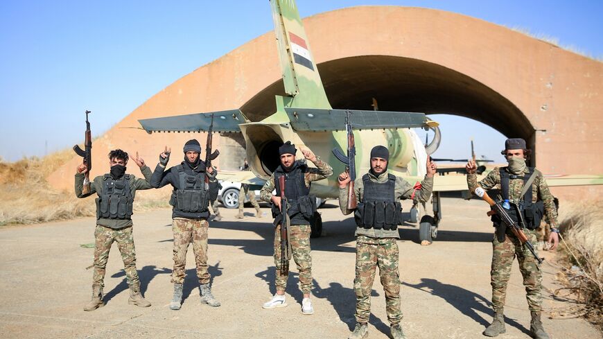 Anti-government fighters pose for a picture in front of a Syrian regime military aircraft at the Kuweires military airfield in the eastern part of Aleppo province, on Dec. 1, 2024. 