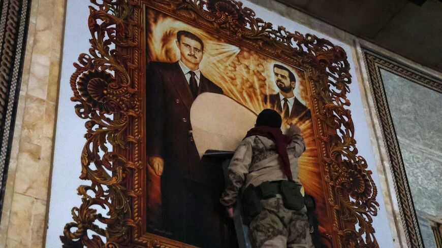 An anti-regime fighter tears off a poster depicting Syrian President Bachar al-Assad (L) and his brother Maher at the airport in the northern Syrian city of Aleppo on Dec. 2, 2024. 