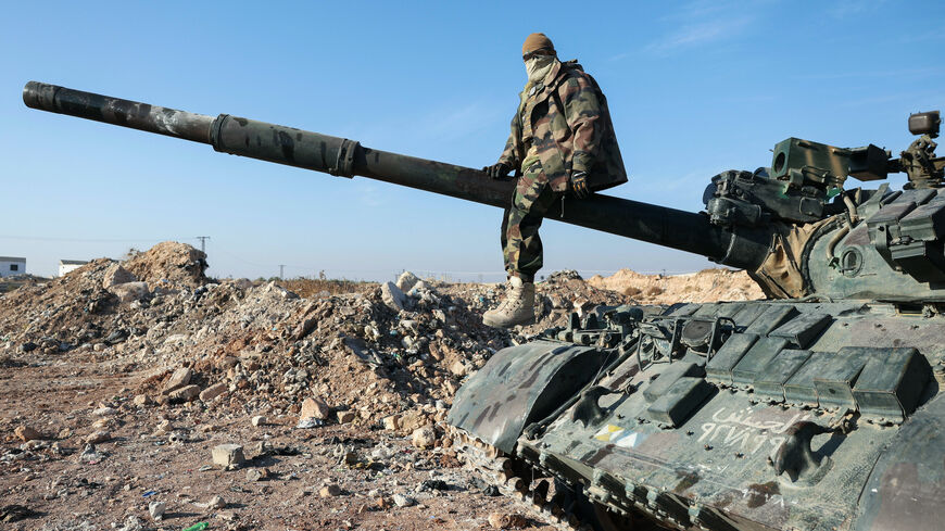 A militant poses for a picture after anti-government fighters seized Syrian army military equipment and vehicles that were abandoned on the highway to Damascus, as they reach the town of Suran north of Syria's Hama city on Dec. 3, 2024. 