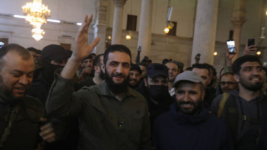 The leader of Syria's Islamist Hayat Tahrir al-Sham (HTS) group that headed a lightning rebel offensive snatching Damascus from government control, Abu Mohammed al-Jolani, waves to the crowd before addressing them at the capital's landmark Umayyad Mosque on December 8, 2024. Jolani, now using his real name Ahmed al-Sharaa, gave a speech as the crowd chanted "Allahu akbar (God is greatest)," a video shared by the rebels on their Telegram channel showed. (Photo by Abdulaziz KETAZ / AFP) (Photo by ABDULAZIZ KE