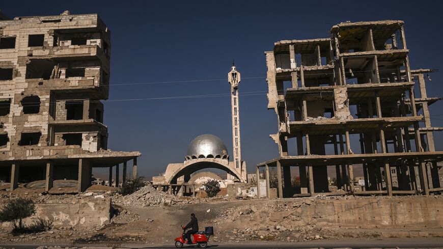 A man rides his scooter past a destroyed mosque and apartment buildings in Harasta, near the Syrian capital, Damascus, on Dec. 19, 2024. 