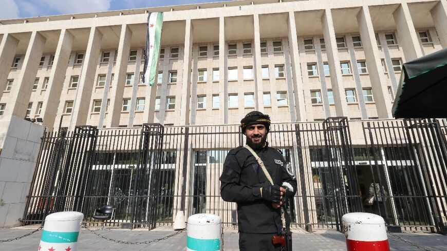 A member of the Syrian security forces stands guard outside the central bank headquarters in Damascus