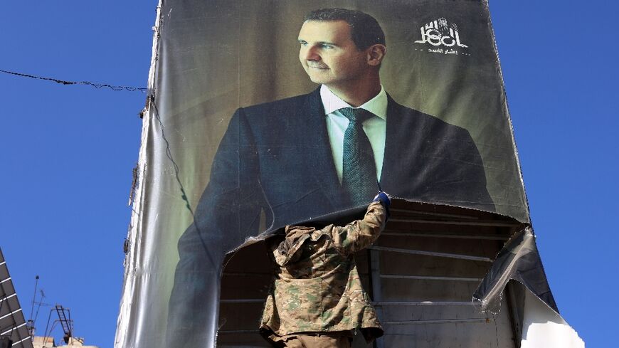 A rebel tears down a picture of Assad in Aleppo