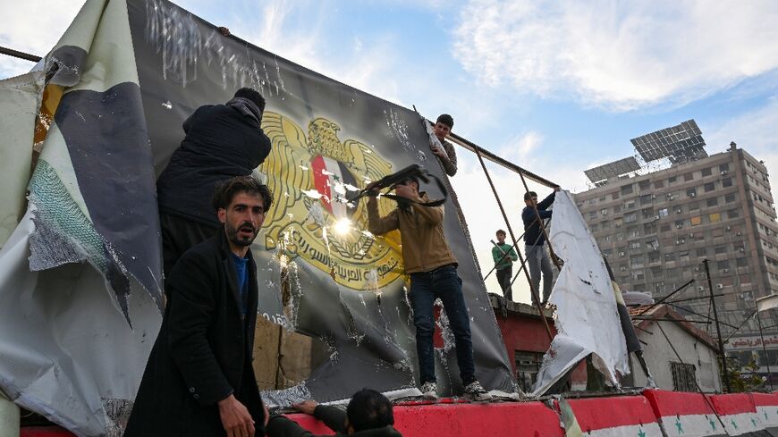 People remove an Assad government banner near Umayyad Square in Damascus