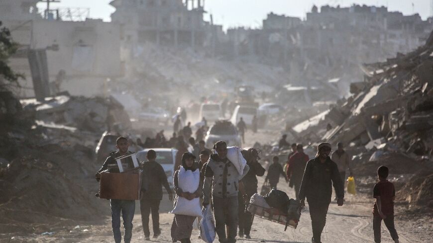 Palestinians carry their belongings as they return to Rafah in southern Gaza, surrounded by destruction