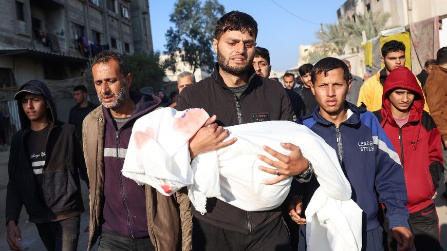 A relative in Khan Yunis, southern Gaza, carries the body of a child, one of four members of the al-Qadra family killed in an Israeli strike before a ceasefire is to take effect