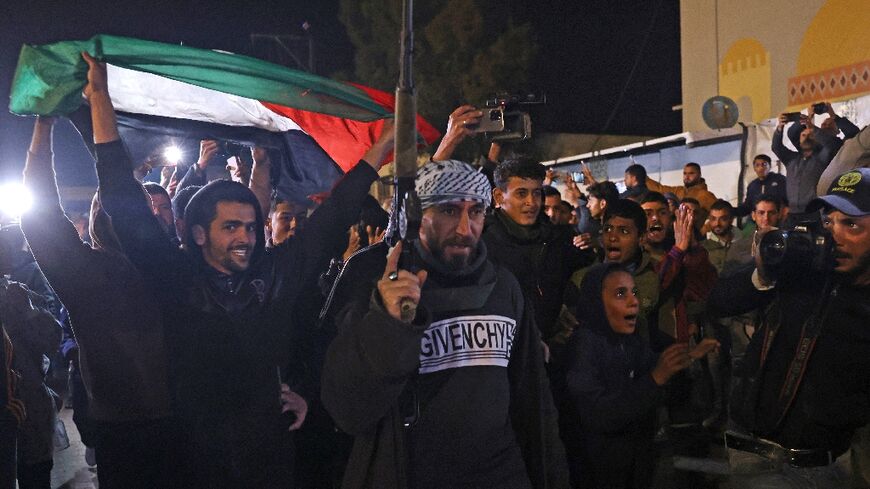 People celebrate while watching a television along a street in Khan Yunis in southern Gaza on January 15, 2025 as news spread that a ceasefire had been reached