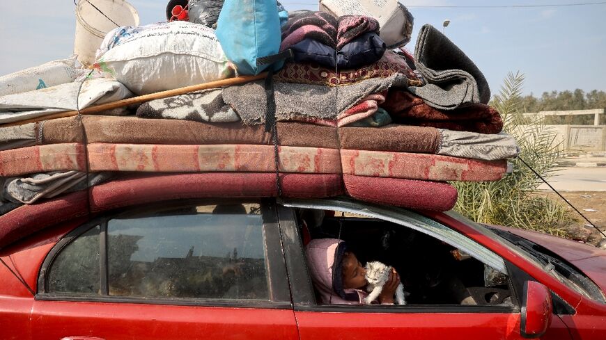 A displaced Palestinian child playes with a kitten in a car on Salah al-Din road in Nuseirat as people make their way to the north of the Gaza Strip