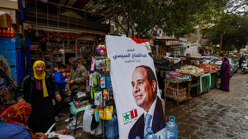 People walk past a campaign poster of Egypt's President Abdel Fattah al-Sisi in a market in Cairo on December 7, 2023, ahead of the presidential election. Egyptian citizens living abroad will cast early ballots on December 8 in a presidential election, in a vote all but certain to give incumbent Sisi a third term in office. (Photo by Khaled DESOUKI / AFP) (Photo by KHALED DESOUKI/AFP via Getty Images)