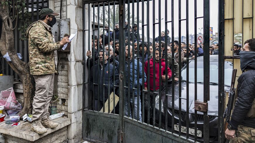 A member of Syria's transitional government security forces calls the names of persons queueing up at a center for handing over small arms and security registration with the new authorities, in Damascus, on Dec. 24, 2024.