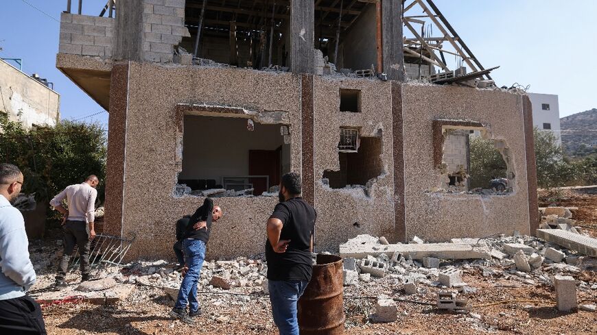 Palestinians inspect the site of an Israeli air strike which killed a man and two children outside their home in the West Bank village of Tammun.