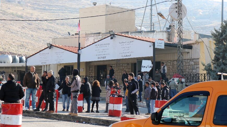 People wait at the entrance to the Masnaa eastern Lebanese border crossing after Syria imposed new restrictions on the entry of Lebanese citizens, according to two security officials