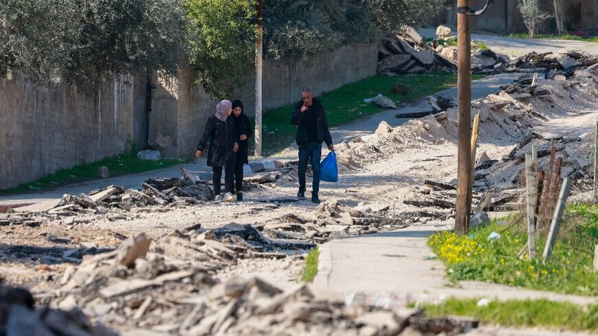 People walk along a road torn up by a bulldozer during an Israeli raid on the Jenin camp for Palestinian refugees 