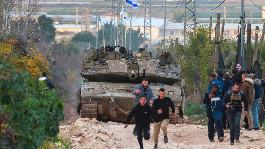 Palestinian children and journalists disperse as Israeli tanks enter the Jenin camp for Palestinian refugees in the occupied West Bank, on February 23, 2025