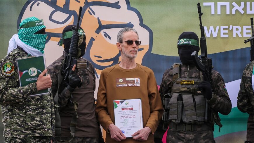 Hamas fighters escort Ohad Ben Ami on a stage before handing him over to a Red Cross team in Deir el-Balah, central Gaza