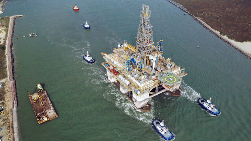 In this aerial image from a drone, tug boats tow the semi-submersible drilling platform Noble Danny Adkins through the Port Aransas Channel into the Gulf of Mexico on Dec. 12, 2020 in Port Aransas, Texas.