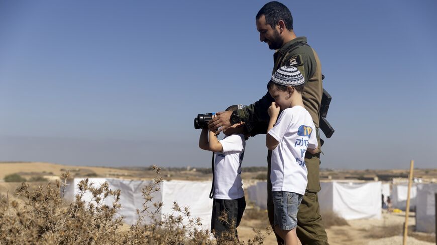 Israeli soldier and kids use binoculars during a Sukkoth gathering, calling for resettling Gaza with Jewish communities near the border with the Gaza Strip on Oct. 21, 2024 in Southern Border, Israel. 