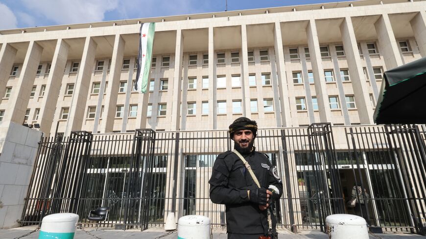 A member of the Syrian security forces stands guard outside the central bank in Damascus, on Dec. 31, 2024. 