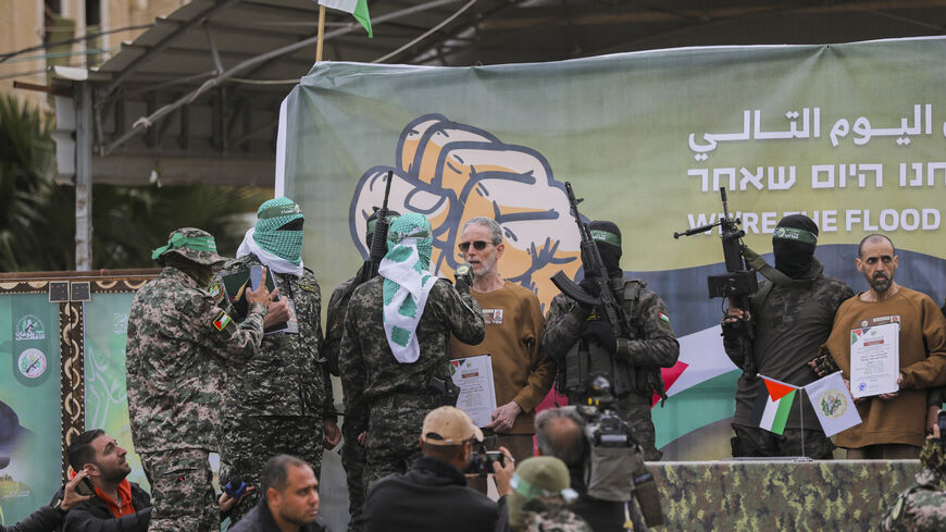 Israeli hostages stand on stage flanked by Hamas militants during the official handover in Gaza, Gaza Strip, on February 8, 2025. Hamas hands over three Israeli hostages to the Red Cross as part of ongoing negotiations. (Photo by Youssef Alzanoun / Middle East Images / Middle East Images via AFP) (Photo by YOUSSEF ALZANOUN/Middle East Images/AFP via Getty Images)