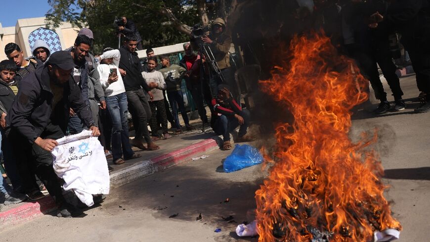 A Palestinian burns a sweatshirt handed to him in Israeli jail, featuring the slogan: "We do not forget and we do not forgive"