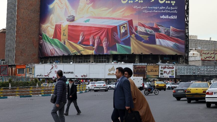 Iranians walk past an illustrated banner depicting the coffin of slain Lebanese Hezbollah leader Hassan Nasrallah, in Tehran