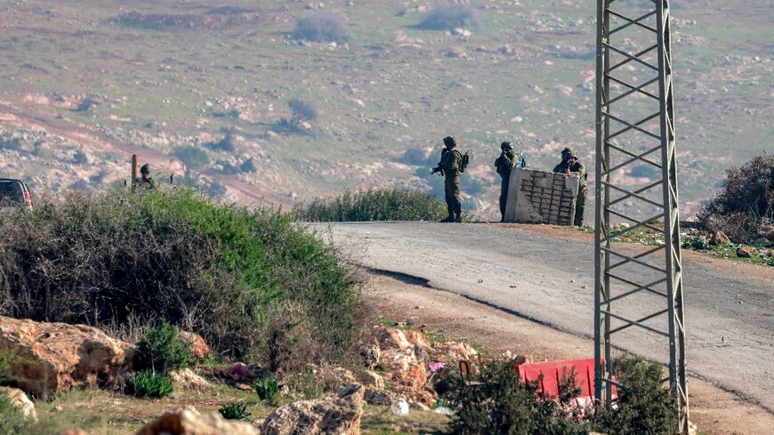 Israeli troops stand guard at the scene of a shooting which fatally wounded two soldiers at a checkpoint in the northern West Bank.