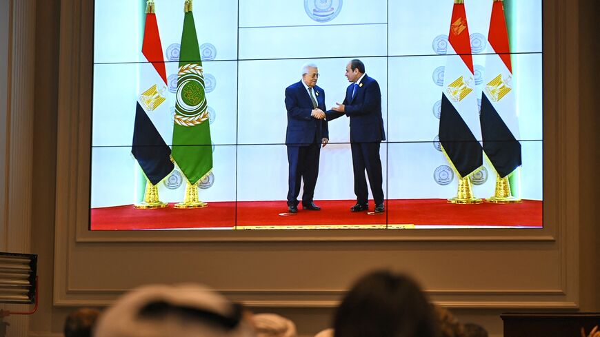 People watch on a big screen as Egypt's president, Abdel Fattah al-Sisi, welcomes Palestinian President Mahmud Abbas ahead of an Arab League summit on Gaza on March 4, 2025.