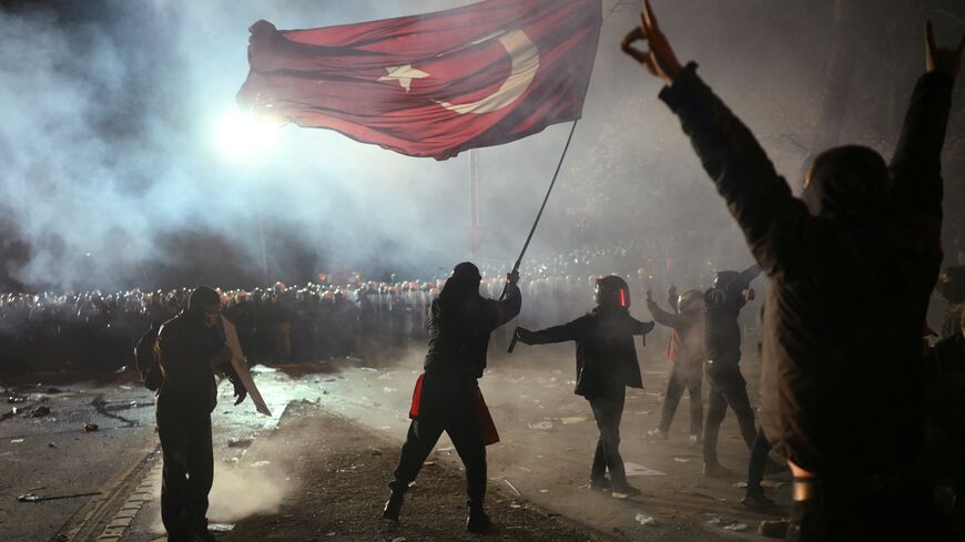 A protestor waves a Turkish flag in front of riot police during a rally in support of Istanbul's arrested mayor in Istanbul, March 24, 2025.