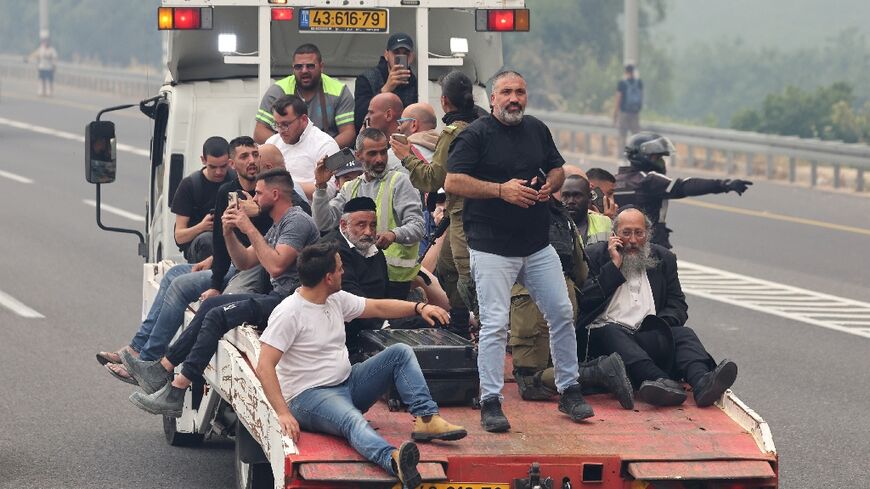 People are evacuated on a recovery vehicle at a highway during a forest fire 