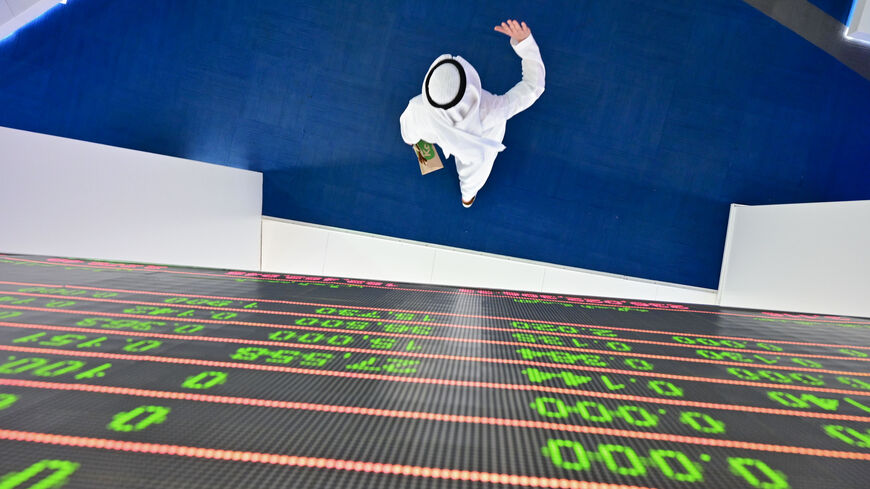 A trader walks by beneath a stock display board at the Dubai Stock Exchange in the United Arab Emirates, on March 8, 2020. - Saudi's stock exchange fell 6.5 percent and other Gulf markets tumbled to multi-year lows at the start of trading after OPEC and its allies failed to clinch a deal over oil production cuts. (Photo by GIUSEPPE CACACE / AFP) (Photo by GIUSEPPE CACACE/AFP via Getty Images)