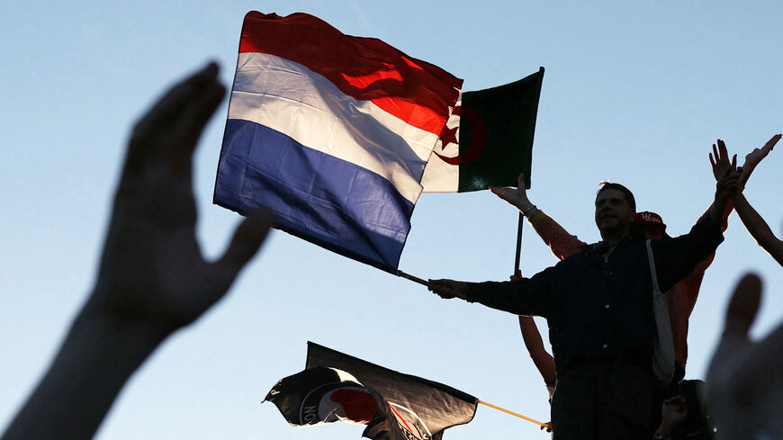 Attendees fly a French national flag and an Algerian national flag during a gathering for the election night following the second round results of France's legislative election at Republique Square in Paris on July 7, 2024. A broad left-wing coalition was leading a tight French legislative election, ahead of both President's centrists and the far right with no group winning an absolute majority, projections showed. (Photo by Alain JOCARD / AFP) (Photo by ALAIN JOCARD/AFP via Getty Images)