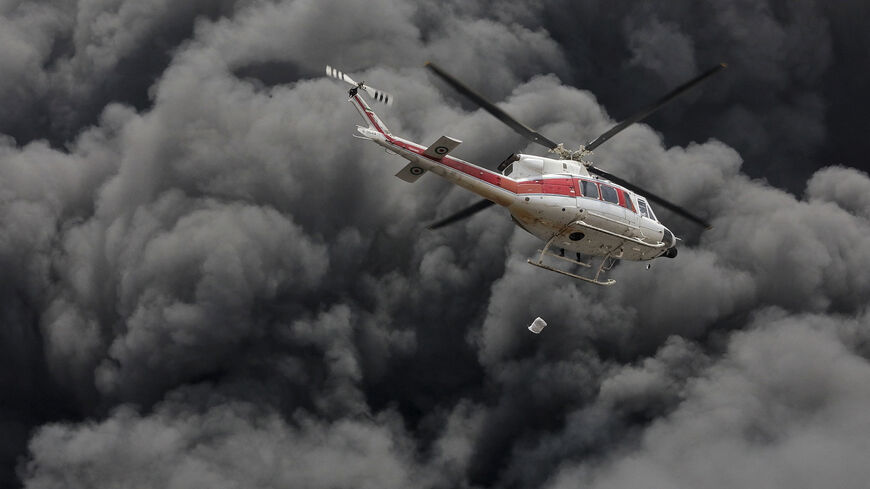 A firefighting helicopter flies through thick clouds of smoke after a deadly explosion at Shahid Rajaee port in Bandar Abbas, Iran, on April 27, 2025. The blast, believed to have originated from hazardous chemicals, killed at least 40 people and injured over 1,200, according to local sources. (Photo by Rahim / Middle East Images / Middle East Images via AFP) (Photo by RAHIM/Middle East Images/AFP via Getty Images)