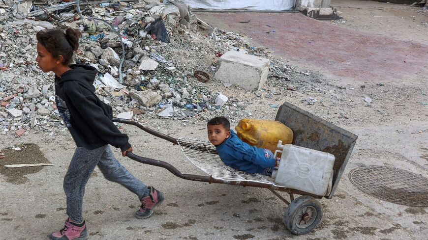 Palestinian children head to a water distribution point to fill their containers in Gaza City