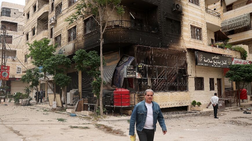 A man walks past a partially burnt building following sectarian clashes in Ashrafiyat Sahnaya near Damascus