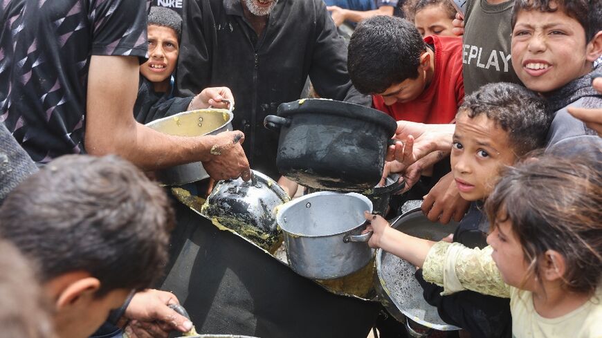 Palestinian children getting a hot food ration from a charity kitchen at the Islamic University campus in Gaza City
