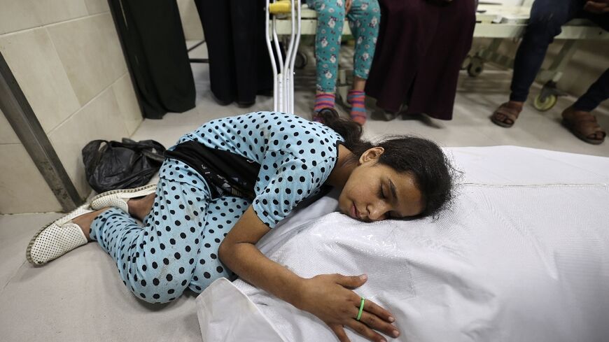 A Palestinian girl mourns over the shrouded body of her mother, killed in a strike