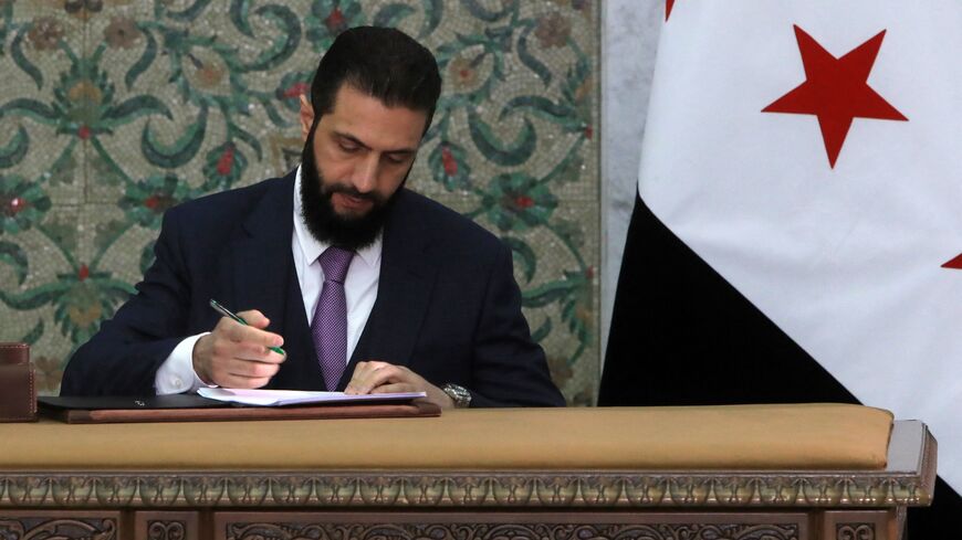 Syria's interim president, Ahmad al-Sharaa, signs the country's constitutional declaration, which will be enforced throughout a five-year transitional period, at the presidential palace in Damascus on March 13, 2025. 