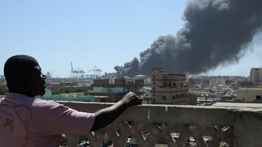 A man watches as smoke billows after a drone strike on the port of Port Sudan on May 6, 2025. Drones struck the airport and targeted an army base in Port Sudan on May 6, officials said, the third straight day the Sudanese army-aligned government's seat of power has come under attack. (Photo by AFP) (Photo by -/AFP via Getty Images)