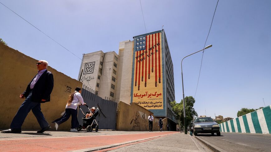 People walk near anti-US mural with the slogan "Down with the USA" and skulls replacing the stars on the flag, in Tehran, on May 20, 2025.