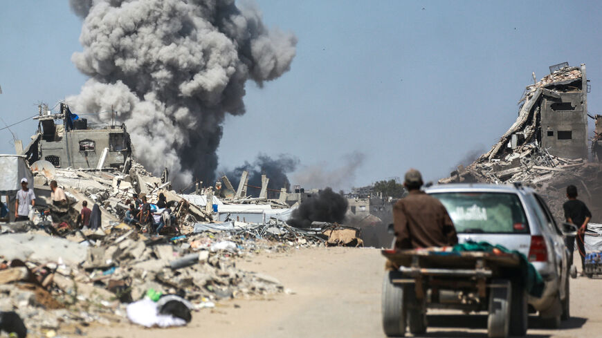People watch as smoke billows following an Israeli strike in Jabalia, in the northern Gaza Strip on May 25, 2025. 