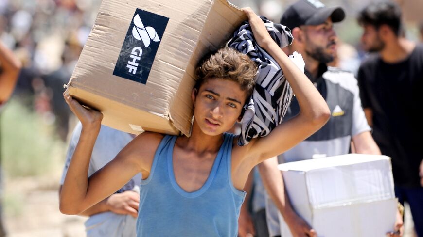 A boy carries a box of supplies from the Gaza Humanitarian Foundation, a private US-backed aid group that has bypassed the longstanding UN-led system