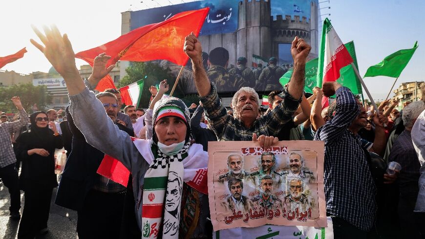 Iranians wave flags and placards during a rally protesting the US attack on Iran in Enghelab Square in Tehran on June 22, 2025