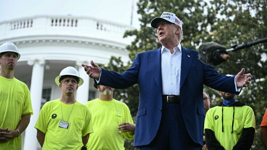 US President Donald Trump speaks to the press as workers install a large flag pole on the South Lawn of the White House in Washington, DC on June 18, 2025
