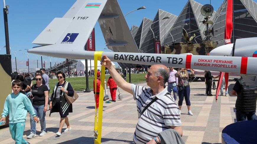 A man poses next to the Bayraktar TB2 drone, manufactured by Turkey's Baykar, as it is presented during the opening of the aerospace and technology festival 'Teknofest Azerbaijan' at Baku Crystal Hall in Baku, on May 27, 2022. 