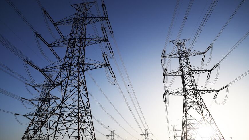 The sun sets behind overhead power lines in Kuwait City as the Kuwaiti Ministry of Electricity requested that citizens ration their electricity usage at peak times due to outages, on June 19, 2024.