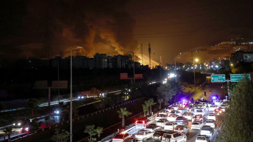 TOPSHOT - Vehicles jam a highway as a fire blazes nearby in the oil depots of Shahran, northwest of Tehran, on June 15, 2025. Israel and Iran exchanged fire on June 14, a day after Israel unleashed an unprecedented aerial bombing campaign that Iran said hit its nuclear facilities, "martyred" top commanders and killed dozens of civilians. (Photo by ATTA KENARE / AFP) (Photo by ATTA KENARE/AFP via Getty Images)