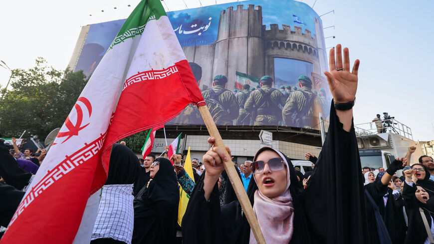 An Iranian woman lifts a national flag during a rally protesting the US attack on Iran in Enghelab Square in Tehran on June 22, 2025. 