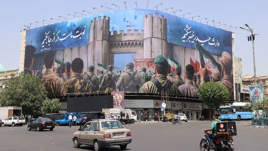 Iranians drive past an anti-Israel poster in Tehran's Enghlab Square
