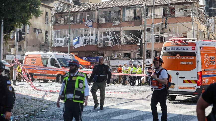 Israeli emergency services stand in front of a building damaged in an Iranian missile attack