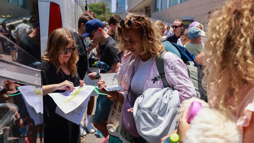 People register before the departure of a bus slated to evacuate foreign passport holders, mainly European and Polish, out of Israel, at a meeting point in Tel Aviv 